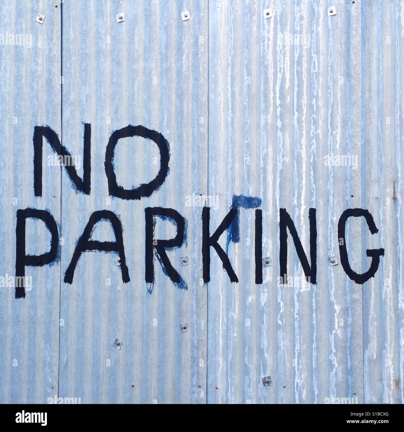 A scribbled No Parking sign on corrugated iron in Bristol, England. - Smartphone Captured Stock Image