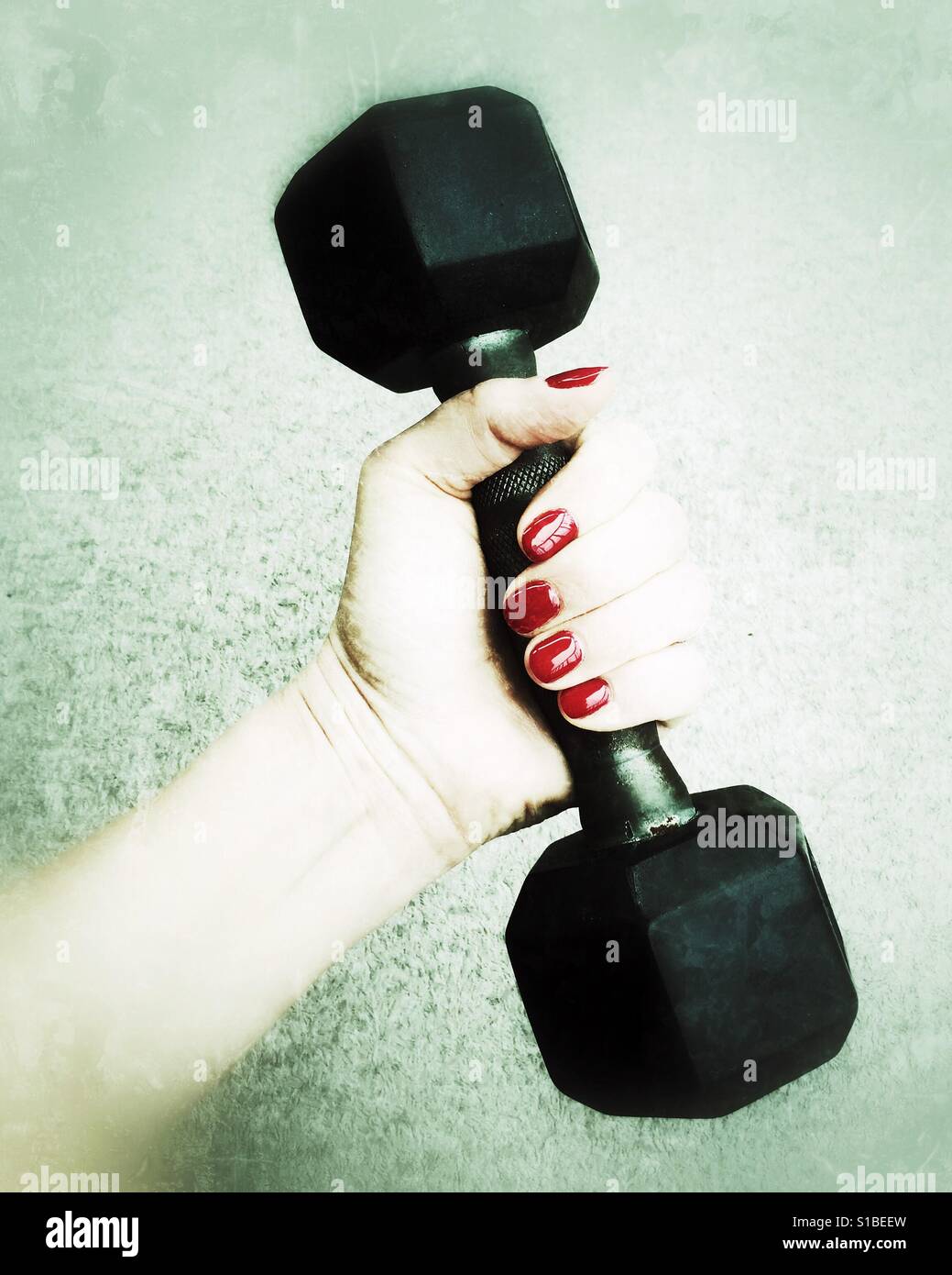 Close up of a woman's hand holding onto a five pound weight. Green hues. - Smartphone Captured Stock Image