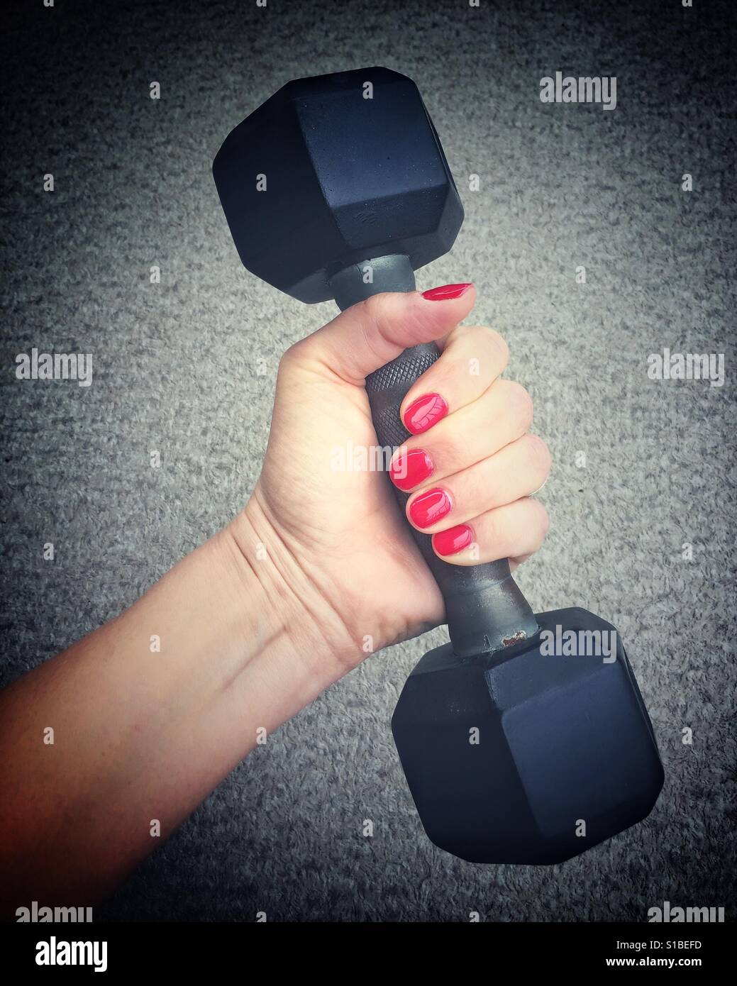 Close up of woman's hand holding onto a five pound weight. Stock Photo