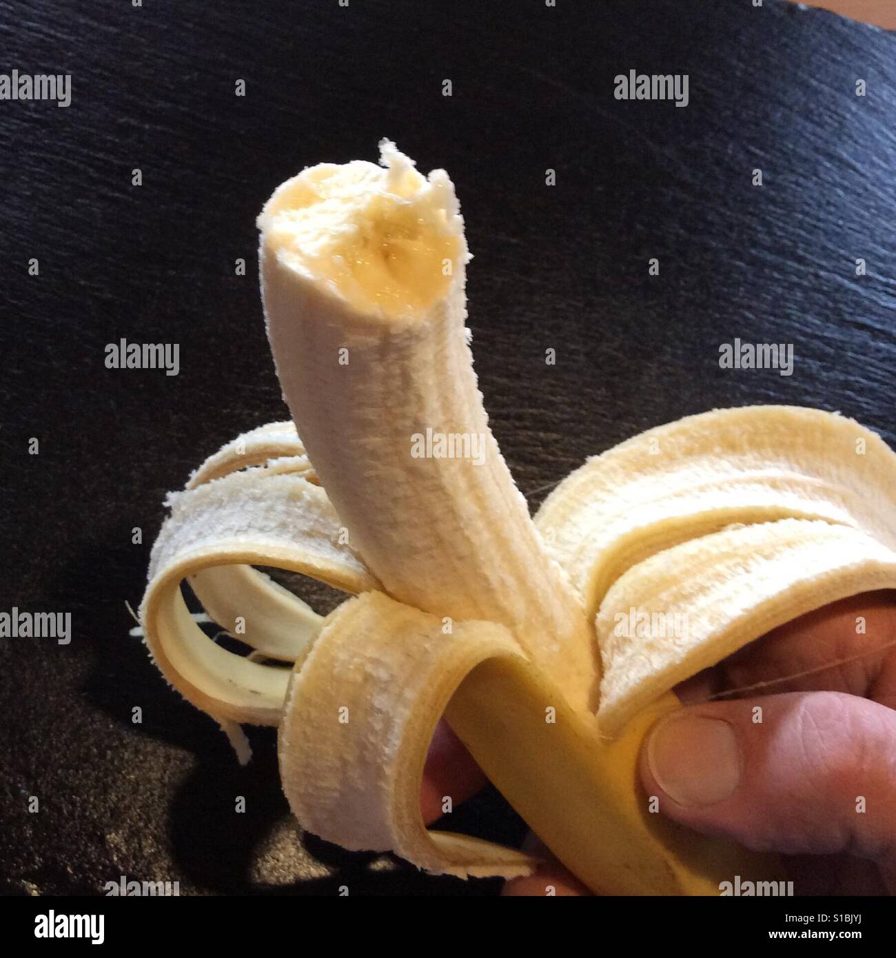 Banana with one bite taken held by female hand Stock Photo