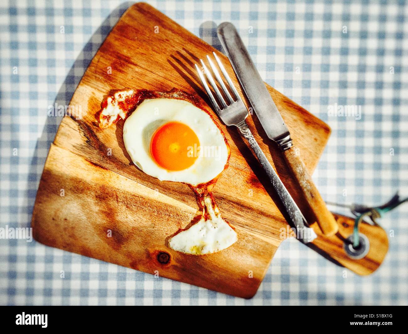 Fried egg on wooden serving board - Smartphone Captured Stock Image