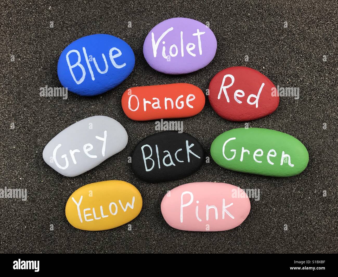 Many colors on stones over black sand - Smartphone Captured Stock Image