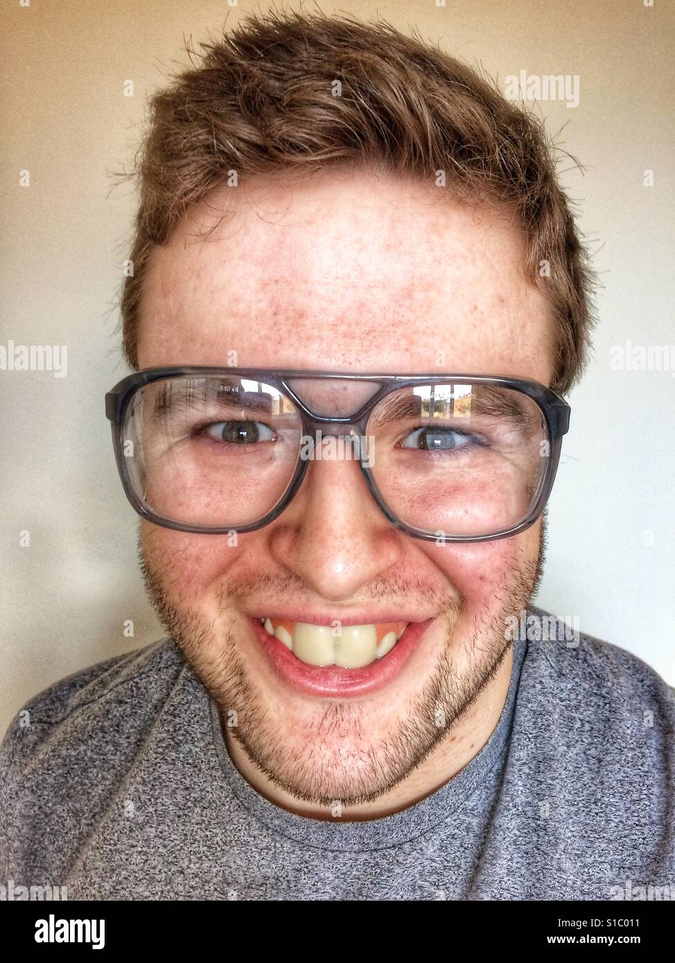 Laughing nerd with buck teeth and big glasses looking straight at the camera. Stock Photo