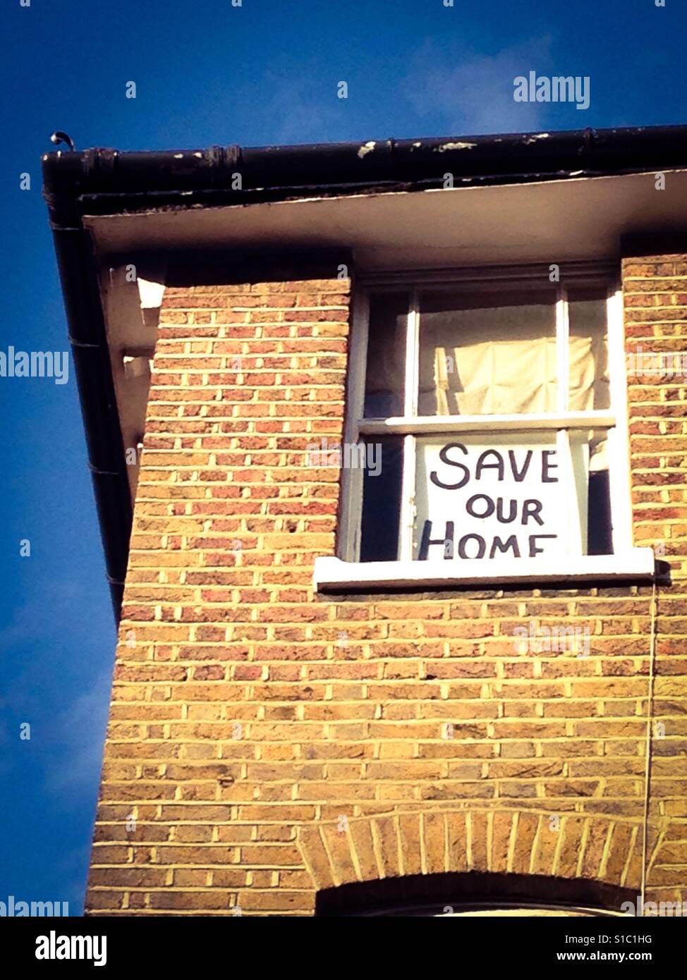 Save our home poster in house window - Smartphone Captured Stock Image