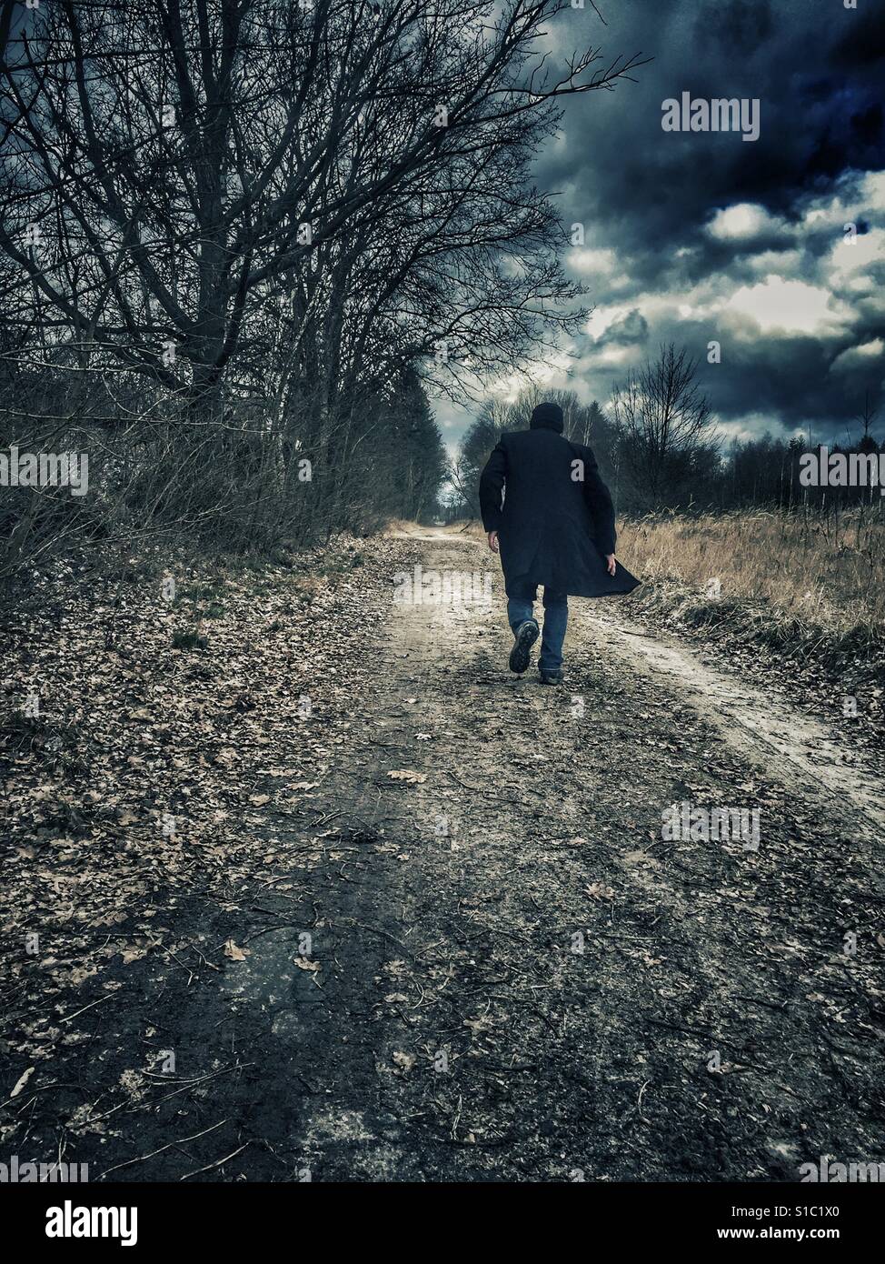 Man wearing a coat running away in the countryside - Smartphone Captured Stock Image