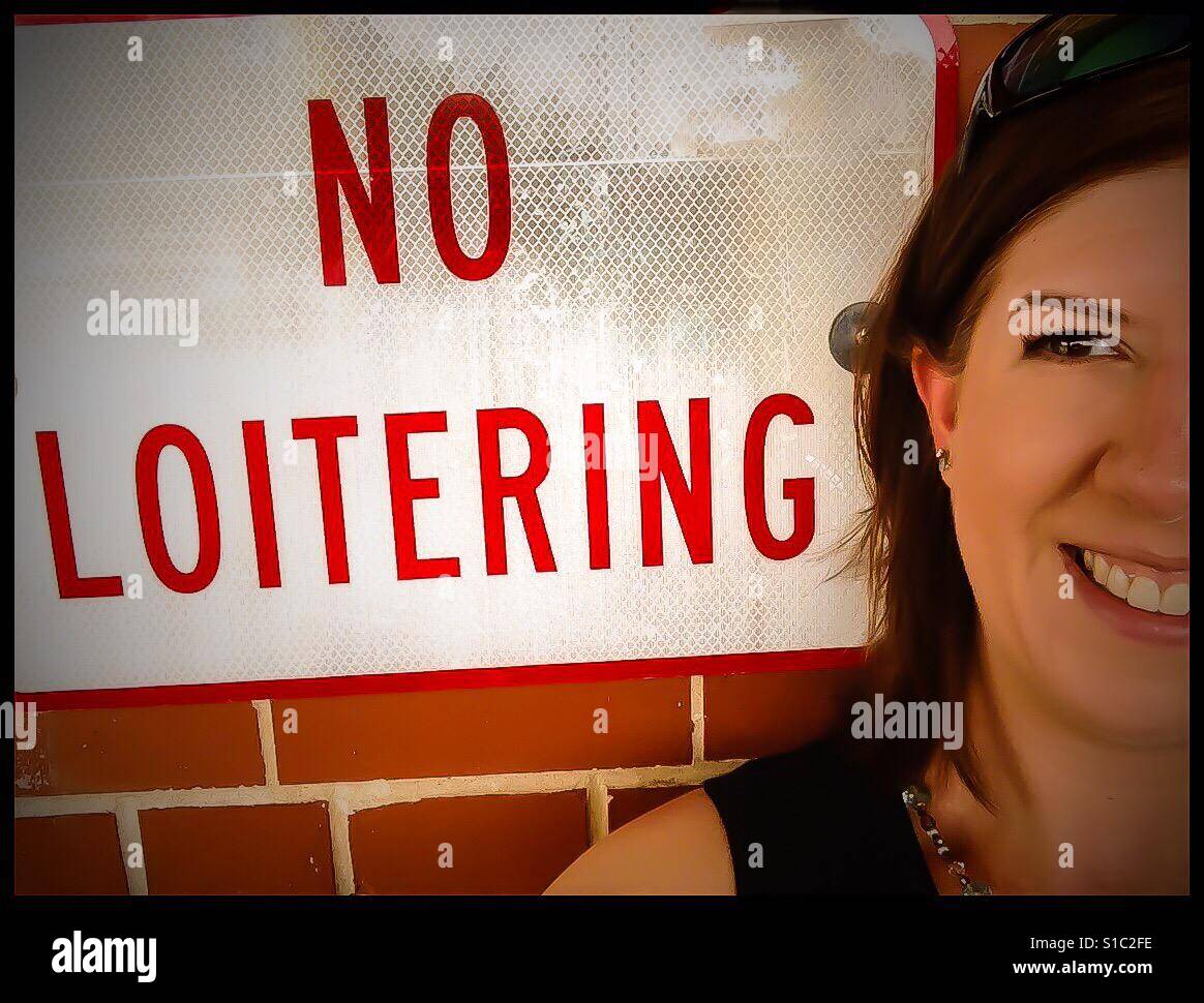 No loitering sign with loitering woman Stock Photo