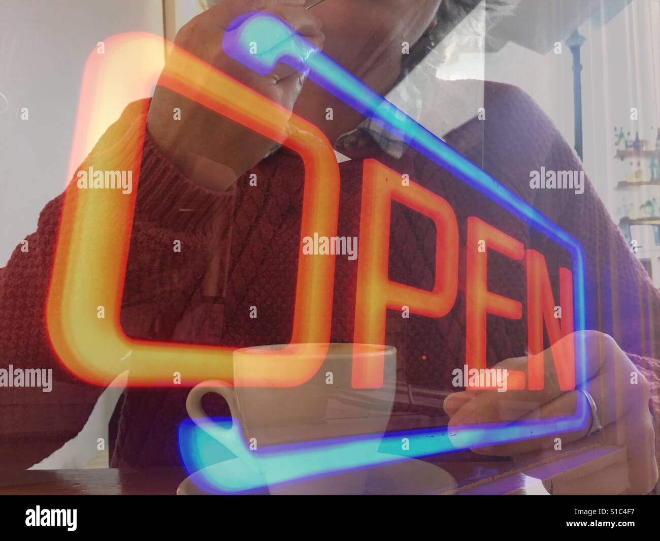 Neon sign of the word Open. Double exposure of woman in a cafe with a coffee - Smartphone Captured Stock Image