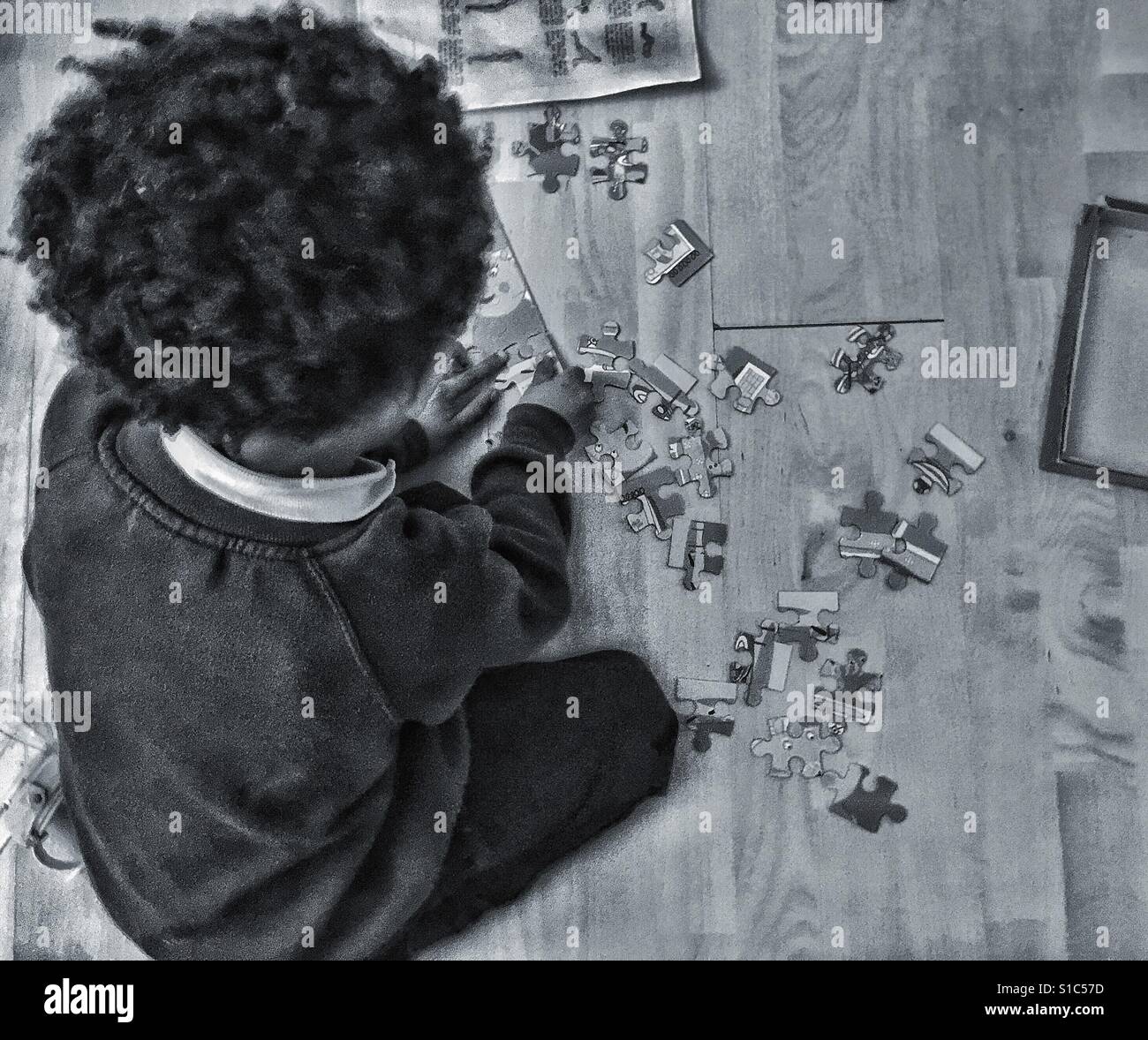 A litre boy seated playing with a jigsaw. - Smartphone Captured Stock Image