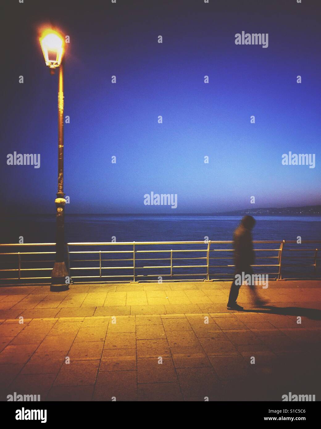 Man walking by the sea at night Stock Photo