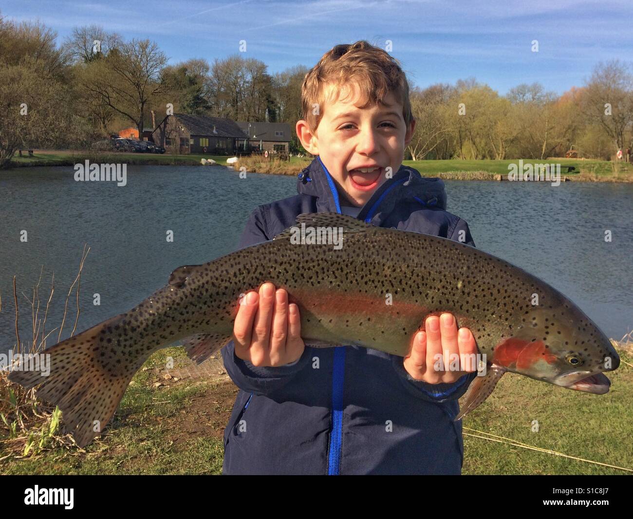 Seven year old boy holding his large rainbow trout fish! Stock Photo