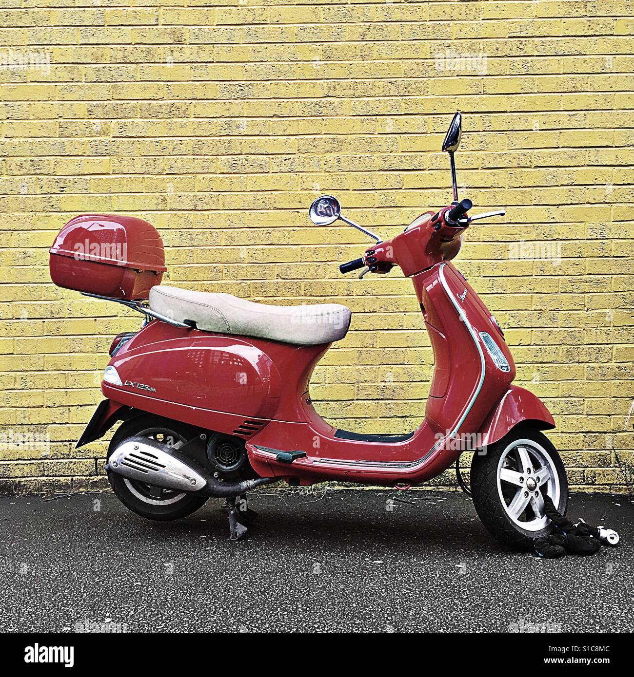 Red vespa against yellow wall Stock Photo