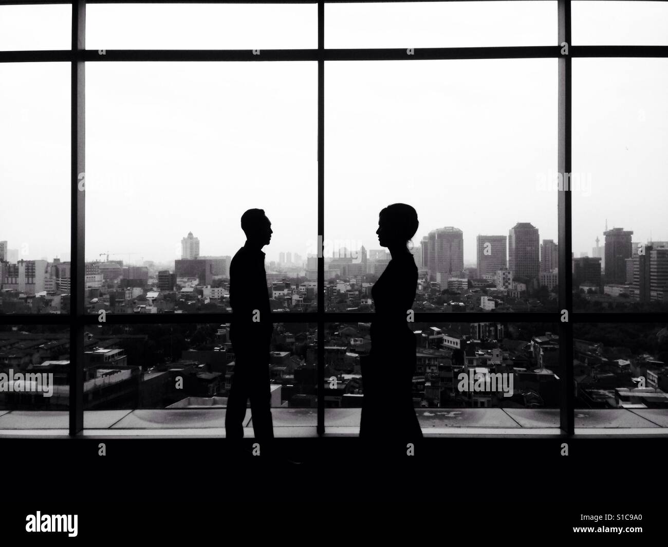 Silhouette of Man and Girl Meet and Walking with Cityscape Landscape View - Black and White Stock Photo
