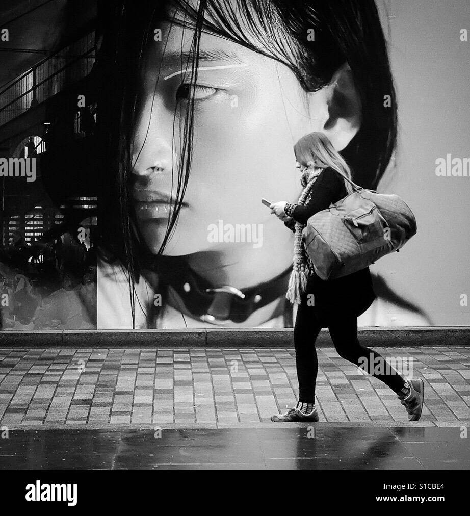 Female walking whilst checking her phone. London, Uk - Smartphone Captured Stock Image