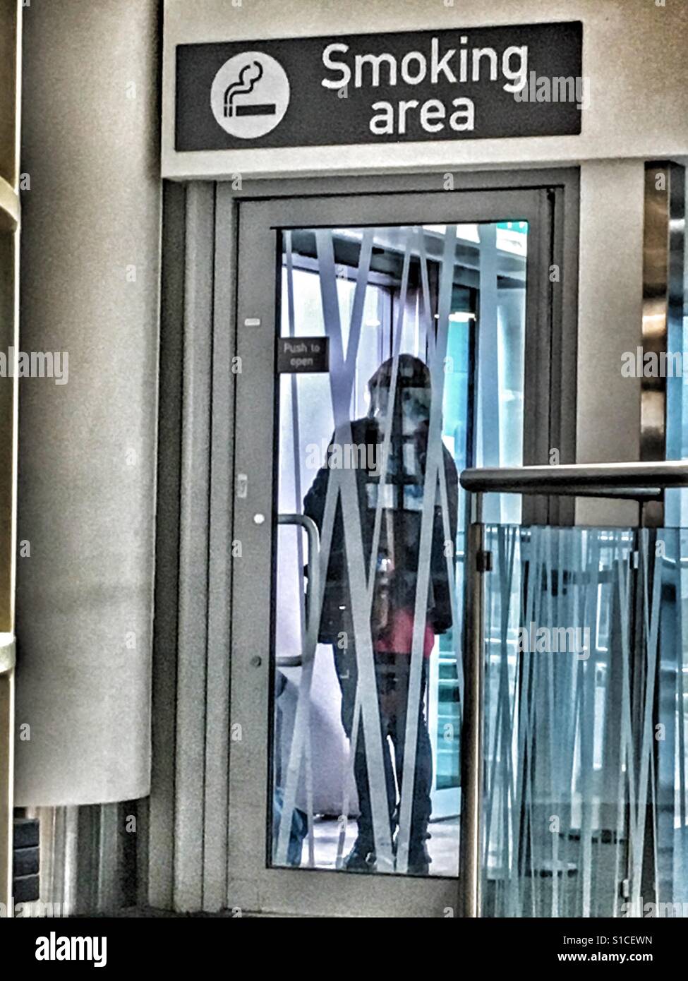 Person behind the closed glass door of the Smoking Area, Bristol Airport,  Uk Stock Photo - Alamy