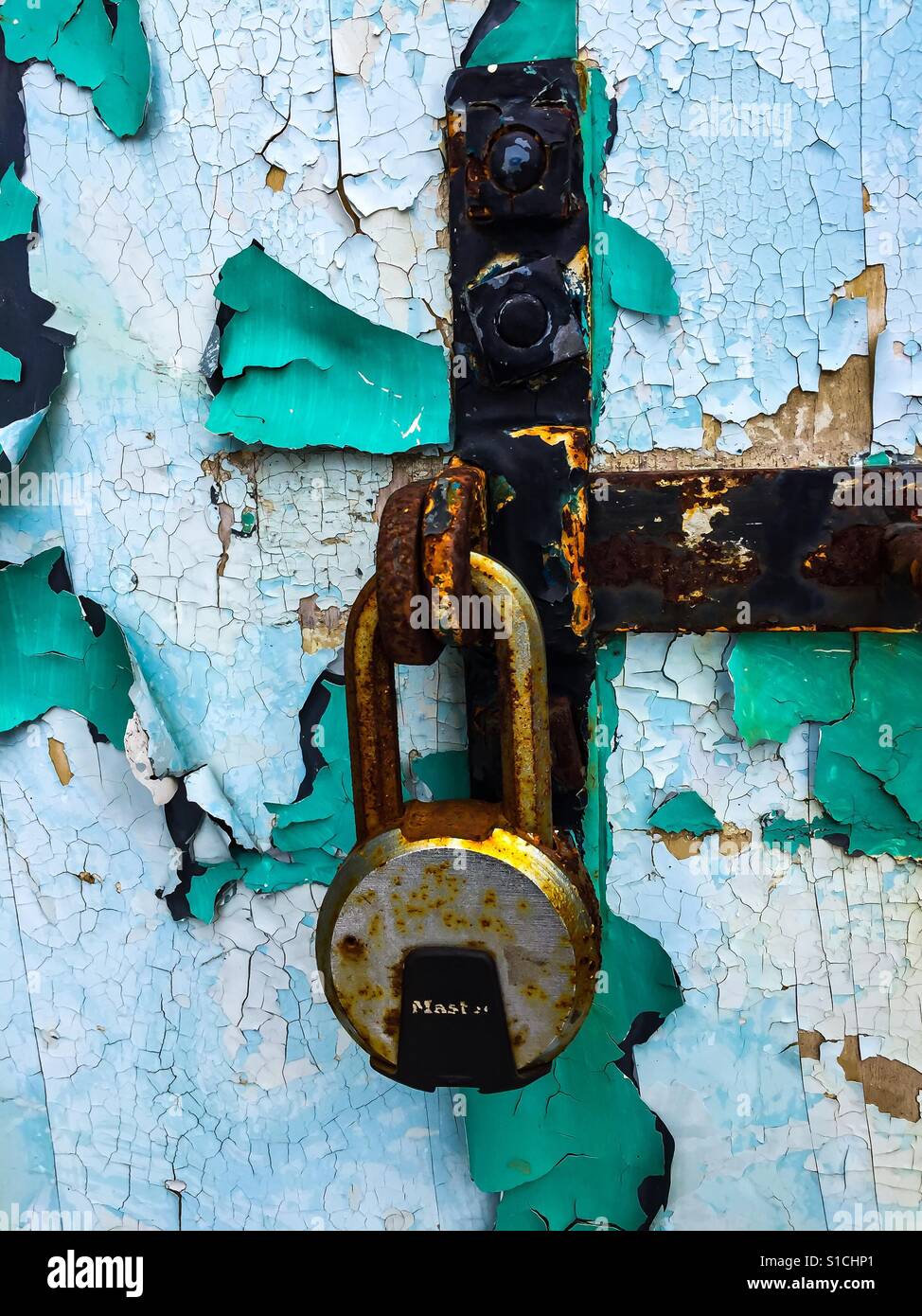 Rust, peeling paint, and padlock, all symbols of the toll time inflicts on all things. Concepts: memories, things past, lost, ravages of time - Smartphone Captured Stock Image