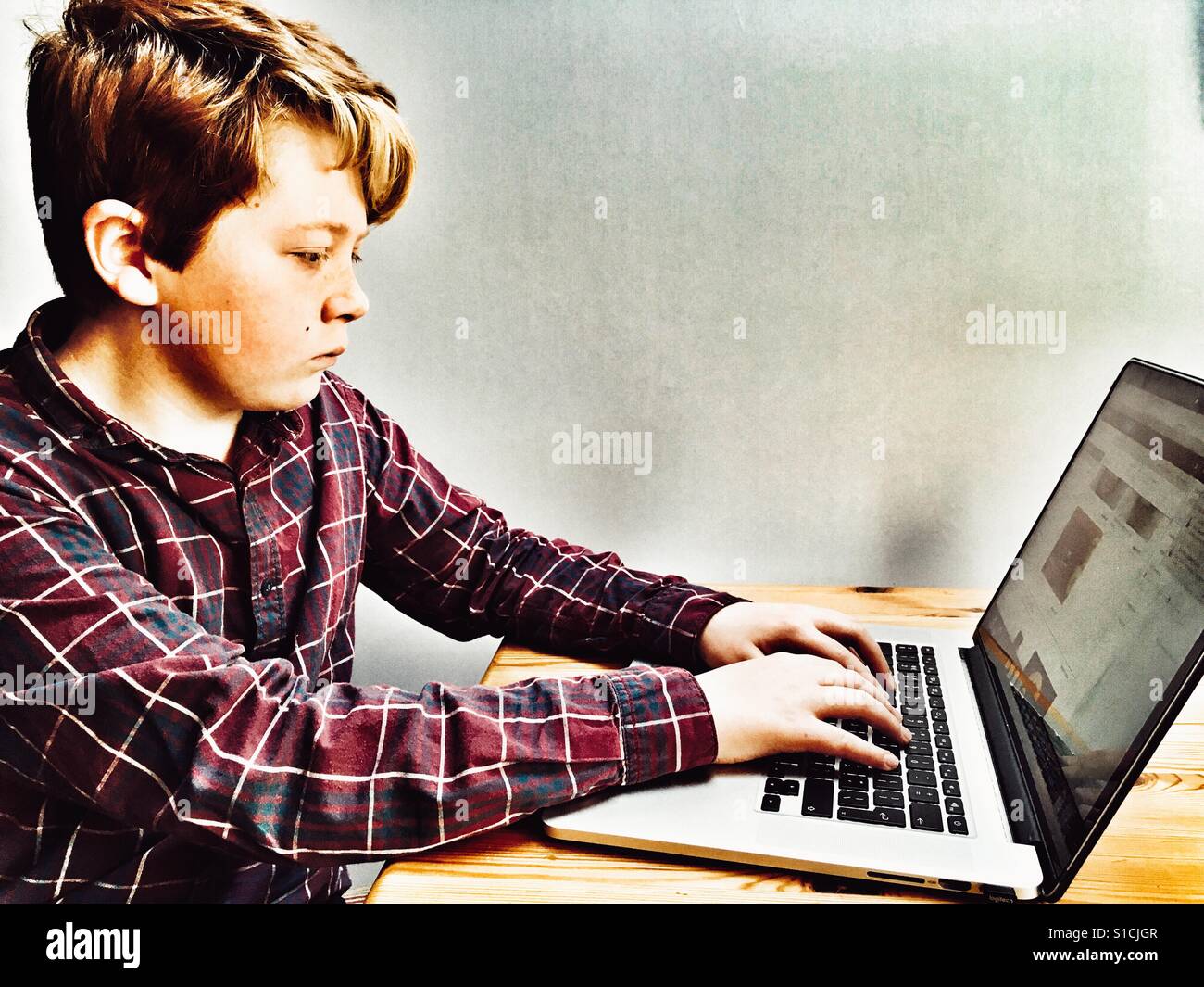 11-year old using laptop computer at home - Smartphone Captured Stock Image