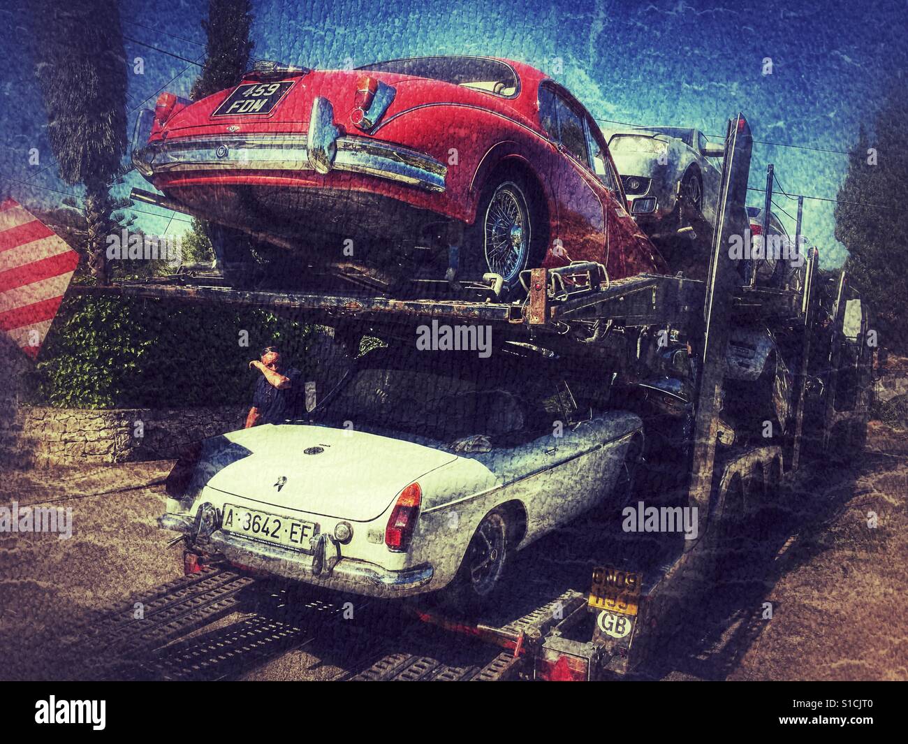Cars including a 1963 Mk 2 Jaguar and a 1973 MGB roadster loaded on to a 8 x car transporter. - Smartphone Captured Stock Image
