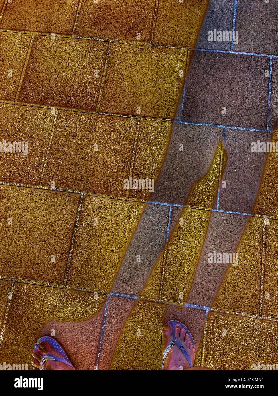 POV Feet in flipflops and shadow on a tiled floor - Smartphone Captured Stock Image