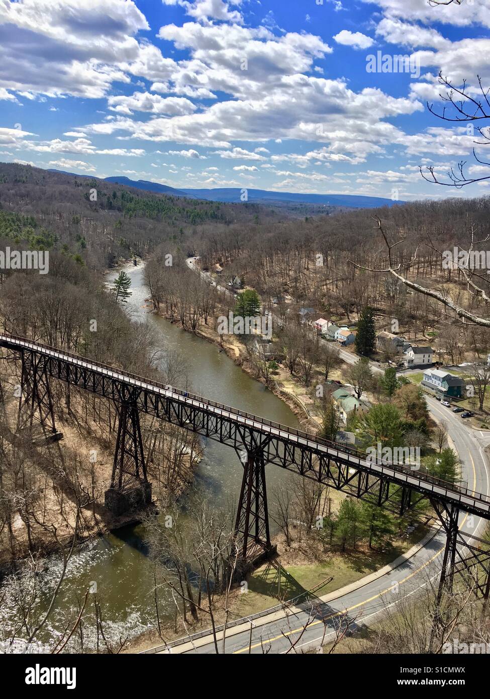 View from hill top of walk way bridge in early spring with happy clouds - Smartphone Captured Stock Image