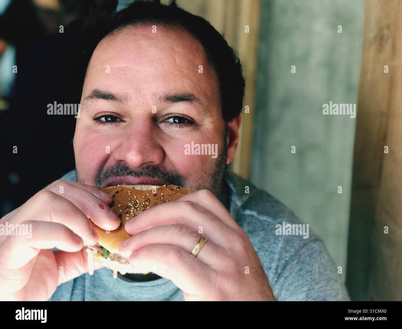 Portrait of man eating burger Stock Photo - Alamy
