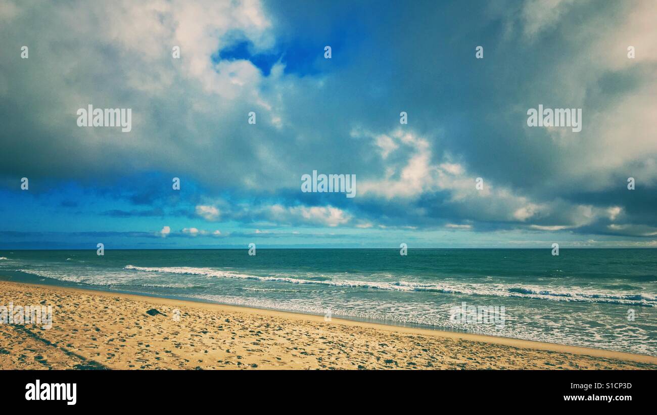 Calm sandy beach with blue sky and white clouds on a sunny day. Retro edit. - Smartphone Captured Stock Image