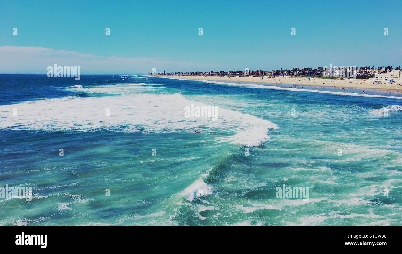 Huntington Beach, California on a sunny and windy spring afternoon. View of the breaking ocean waves and miles long sandy beaches from the pier. March 2017. - Smartphone Captured Stock Image