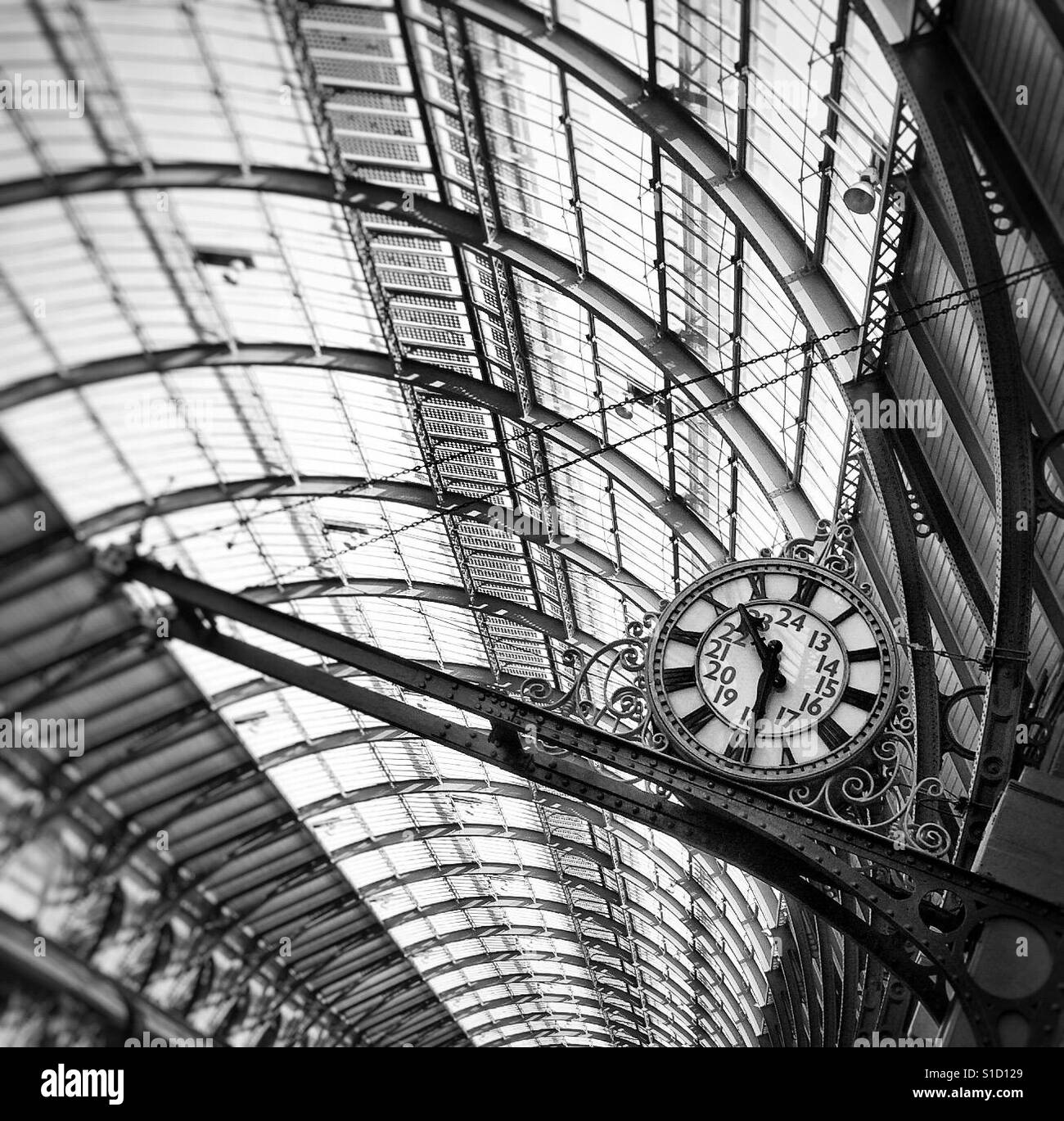 Kings Cross Station, London featuring a clock and the architectural features of the station roof, captured in black and white - Smartphone Captured Stock Image