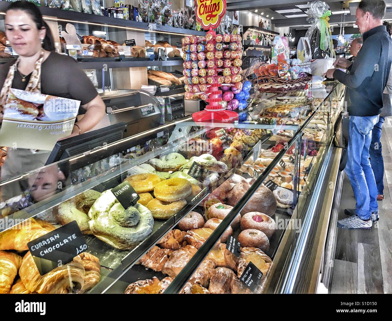 Cafe Wien & Pasteleria Austriaco in Javea, Spain. Interior view at the counter with display of pastries and customers at the counter. - Smartphone Captured Stock Image