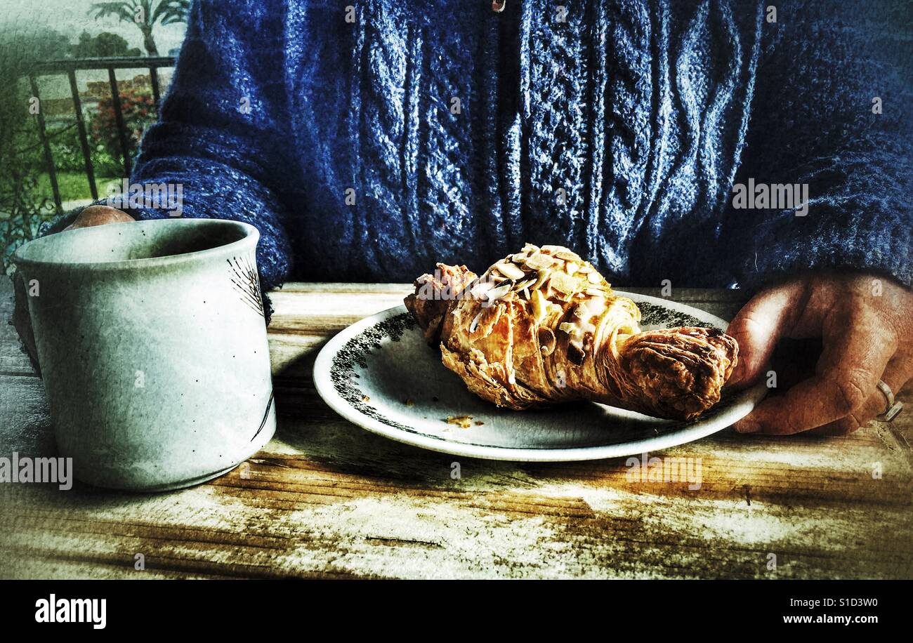 Woman enjoying a hot drink and almond croissant - Smartphone Captured Stock Image