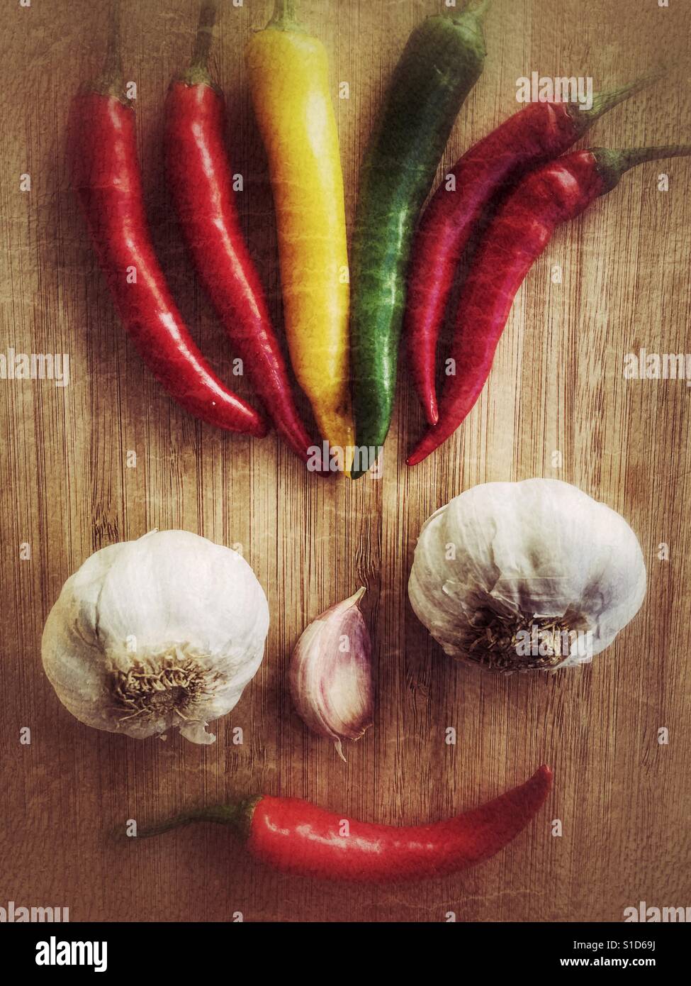 Food art. Smiley face with mad hair, made of fresh garlics and Chillies - Smartphone Captured Stock Image