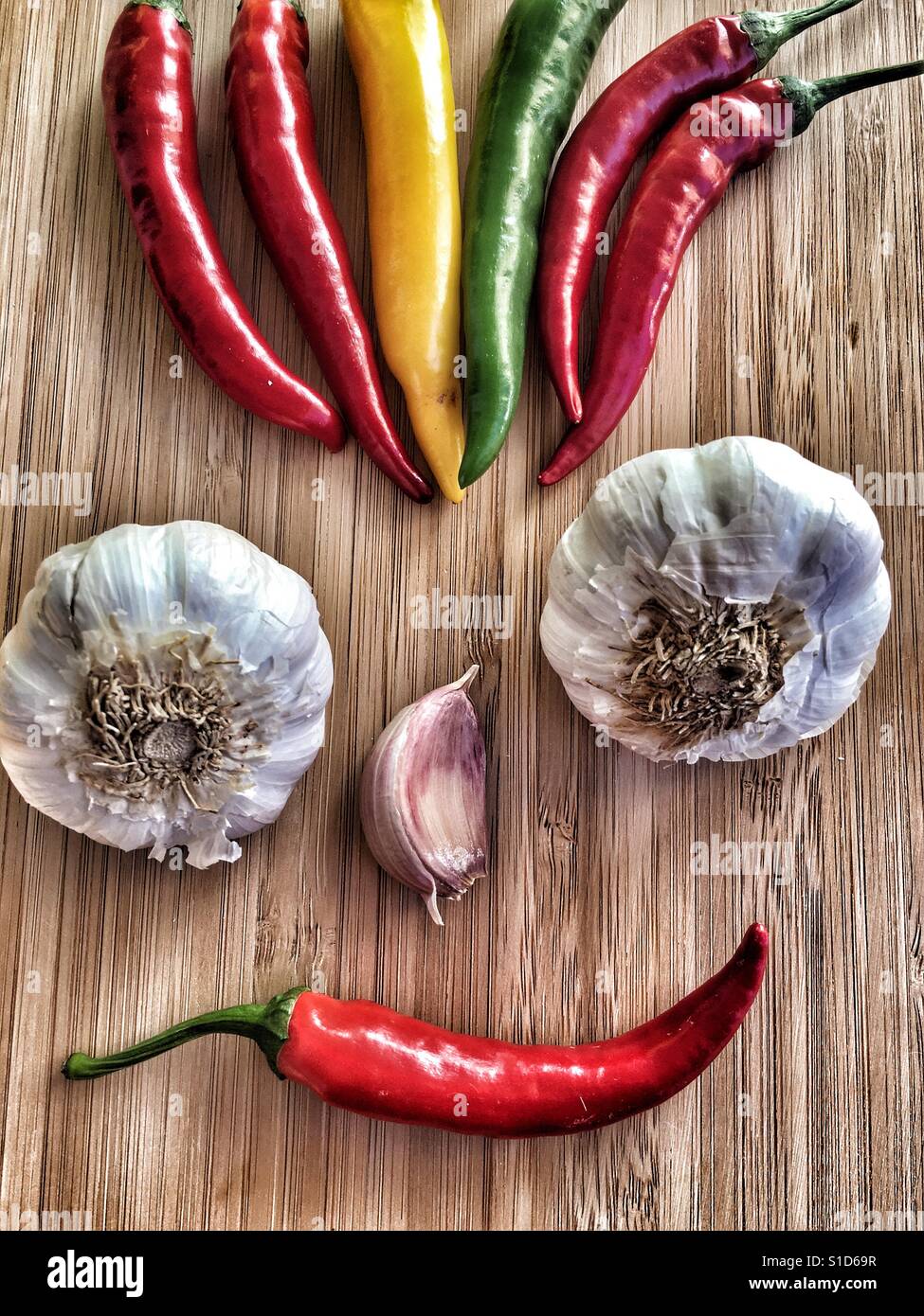 Food art. Smiley face with punk hair made from fresh chillies and garlic. - Smartphone Captured Stock Image