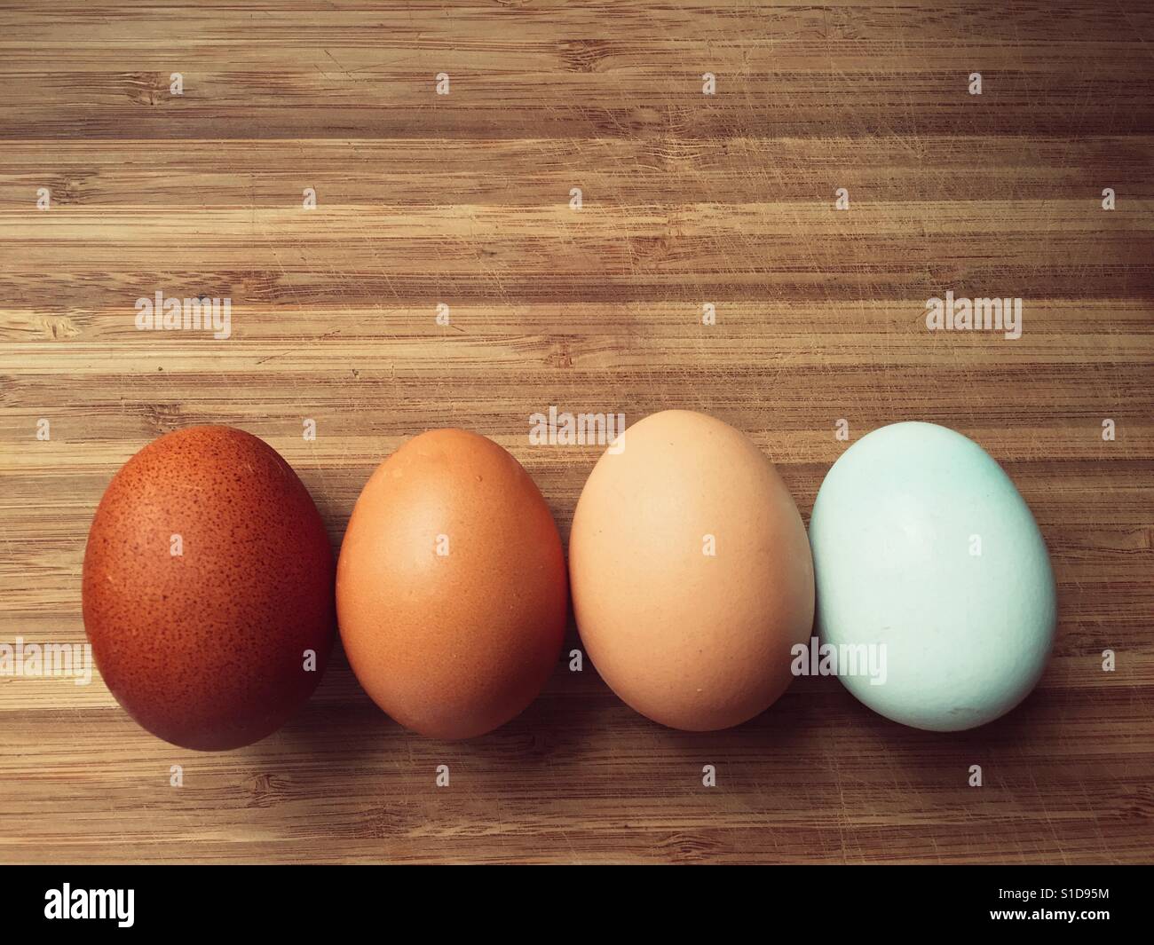 Four eggs in different shades on a wooden surface - Smartphone Captured Stock Image