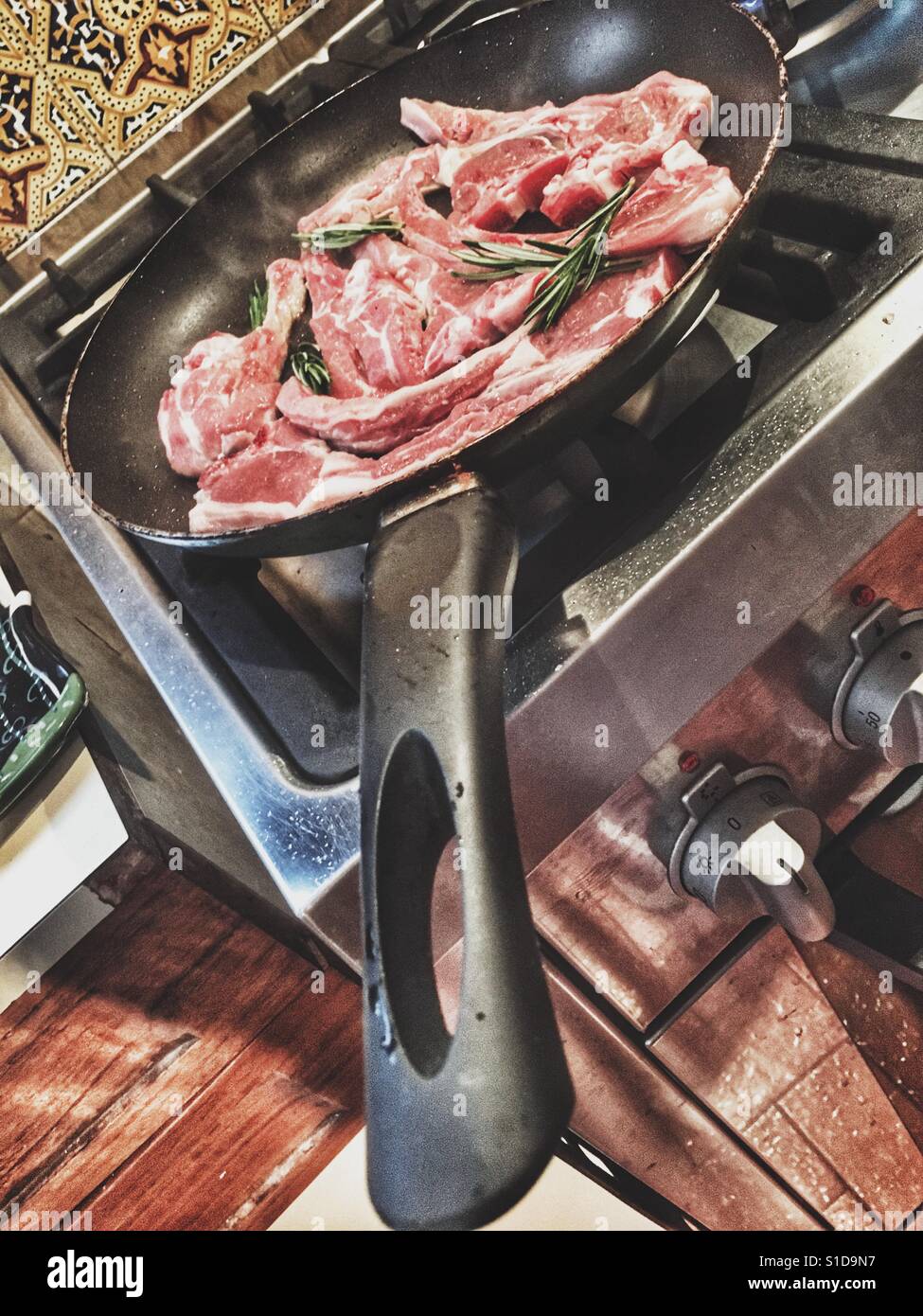 Lamb chops in a frying pan with fresh rosemary, on the stove Stock