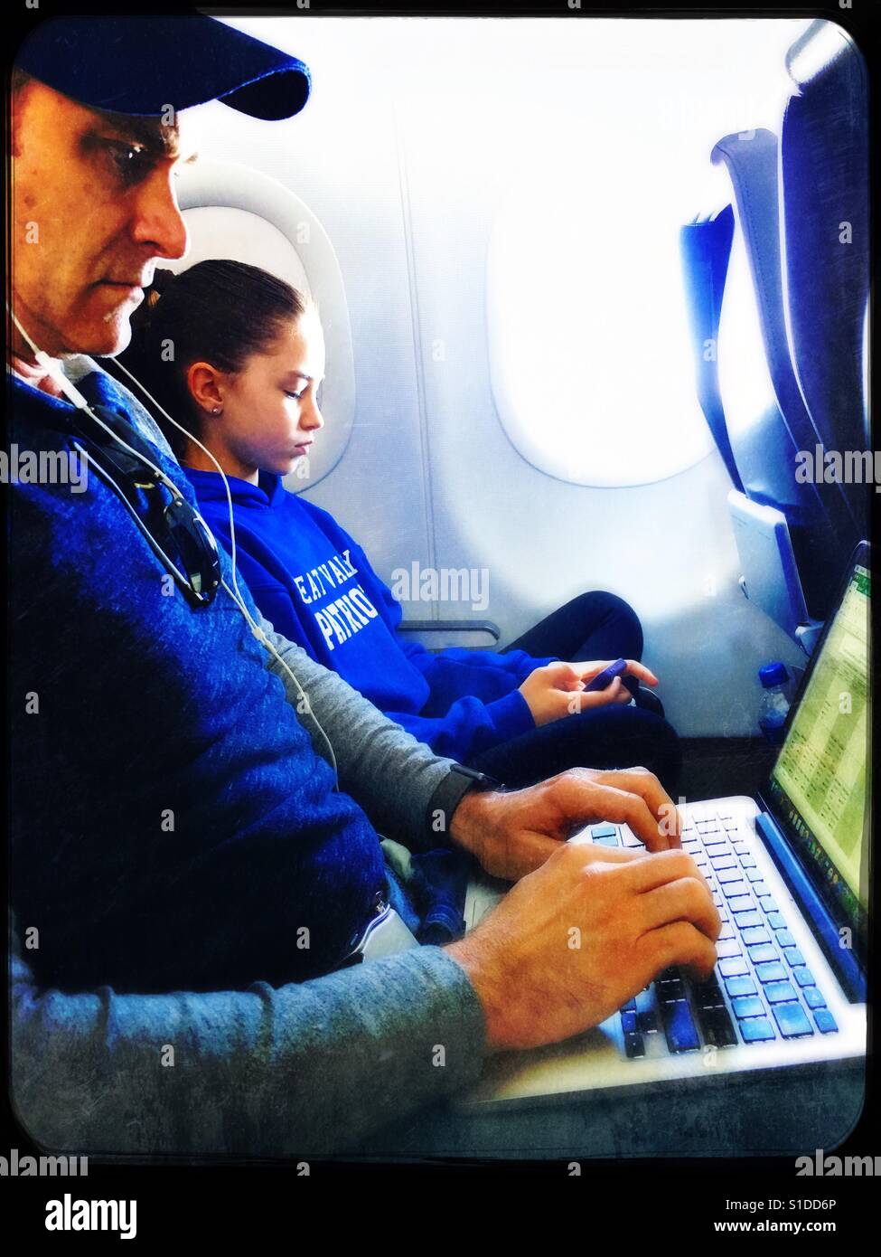 Father and daughter using technology on airplane - Smartphone Captured Stock Image