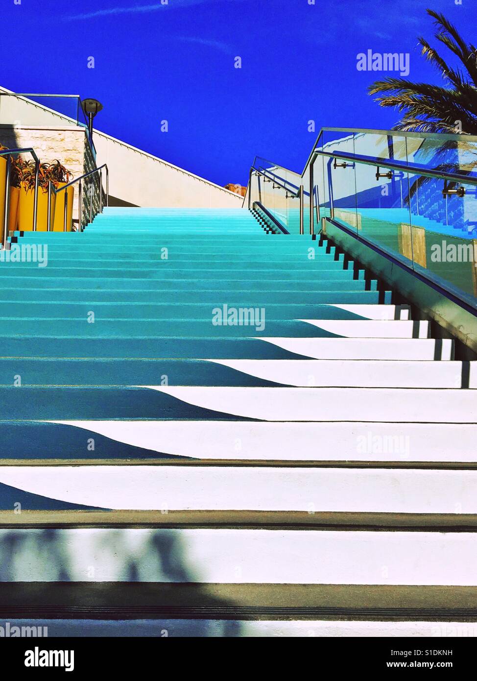 Stairs painted different shades of blue leading up towards a bright blue sky. - Smartphone Captured Stock Image