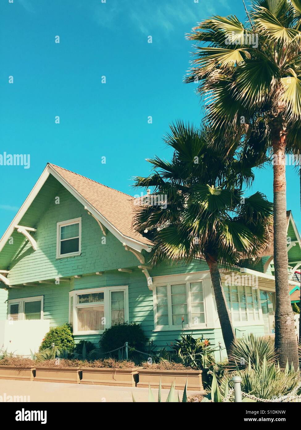 Charming old wood house and palm trees under a bright blue sky on a sunny day. Stock Photo