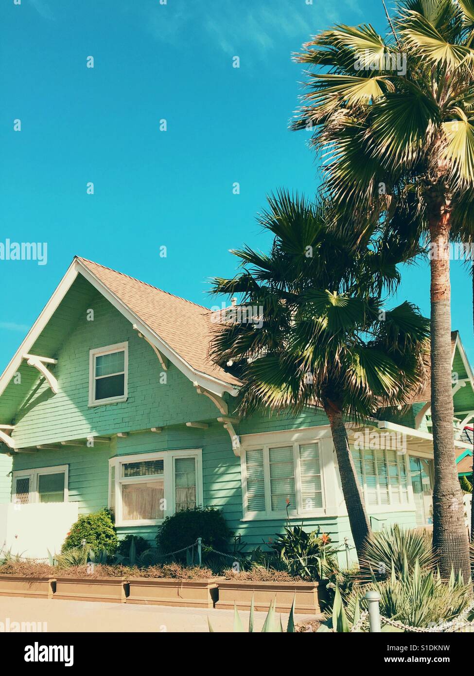 Charming old wood house and palm trees under a bright blue sky on a ...