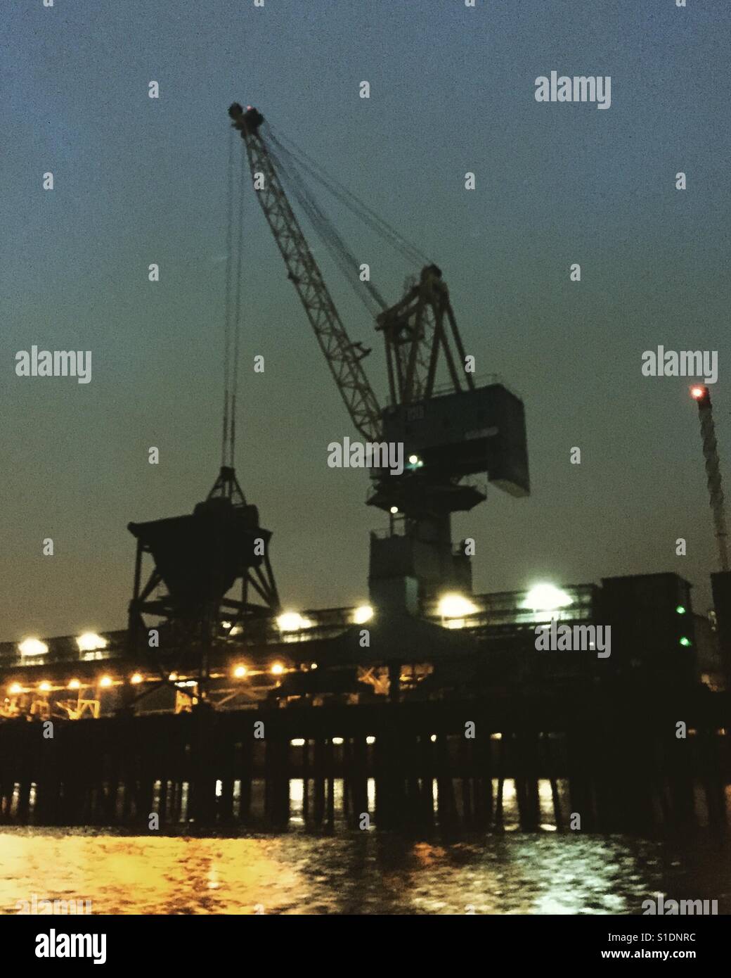 Dockside crane on a wharf by the river Thames, looming out of the dusk - Smartphone Captured Stock Image