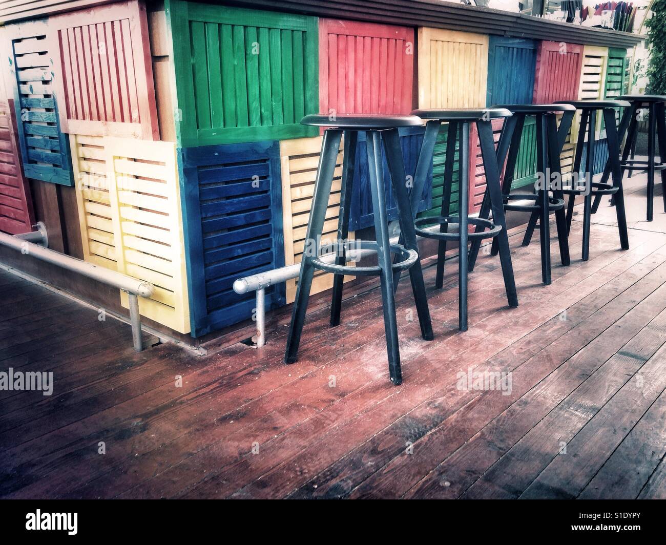 Row of stools at colorful wooden bar Stock Photo