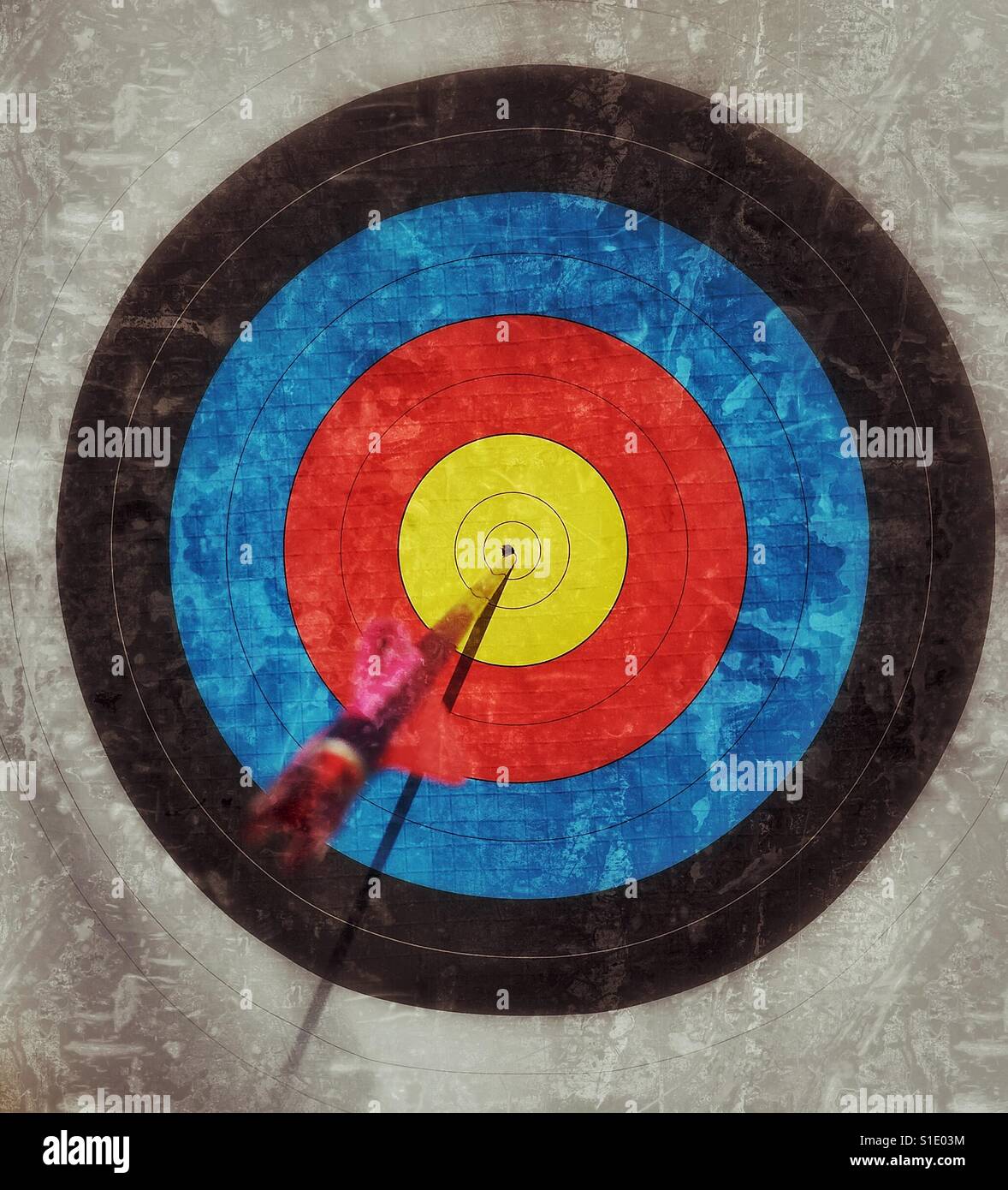 BULLSEYE! The perfect archery shot. A grunge effect image of an arrow in the dead centre of an archery target. Photo Credit © COLIN HOSKINS. - Smartphone Captured Stock Image