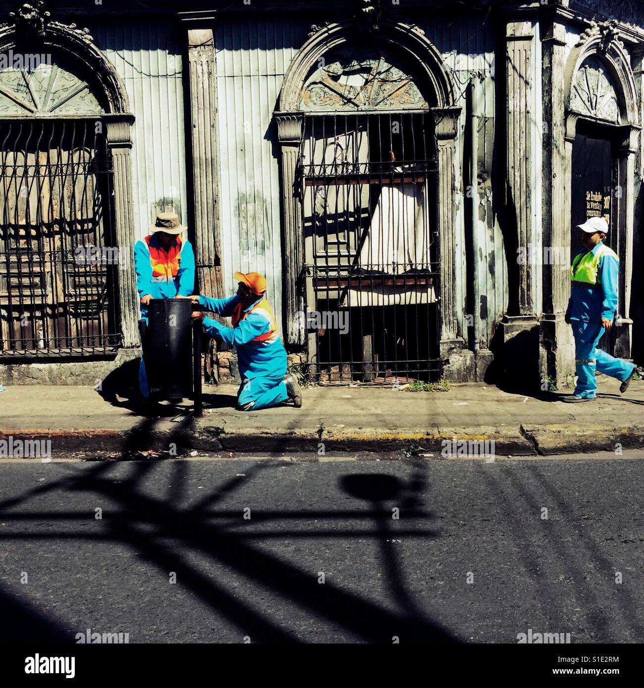 Salvadoran garbage collectors work in front of a ruined house, designed by using bold Spanish colonial architecture elements, built in the center of San Salvador, El Salvador, 10 November 2016. Stock Photo