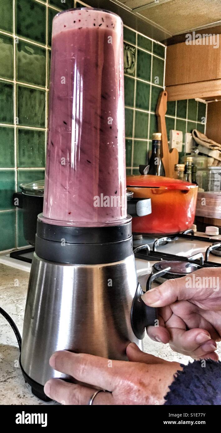 Healthy lifestyle. Woman making a fruit smoothie at home, close up of hands and blender - Smartphone Captured Stock Image