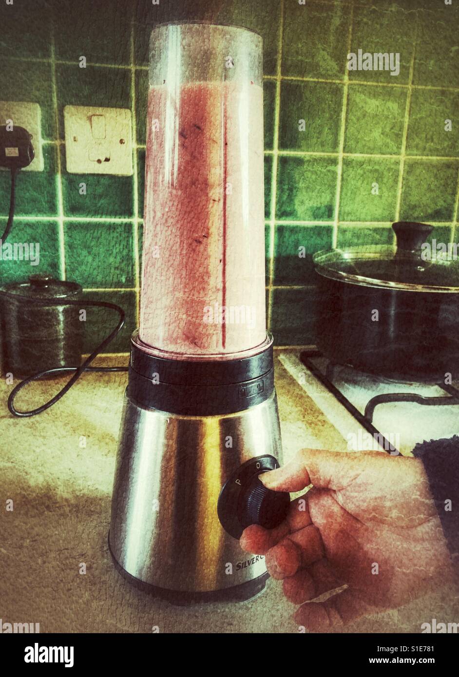 Healthy lifestyle. Woman making at fresh fruit smoothie, with hand on the blender knob. - Smartphone Captured Stock Image