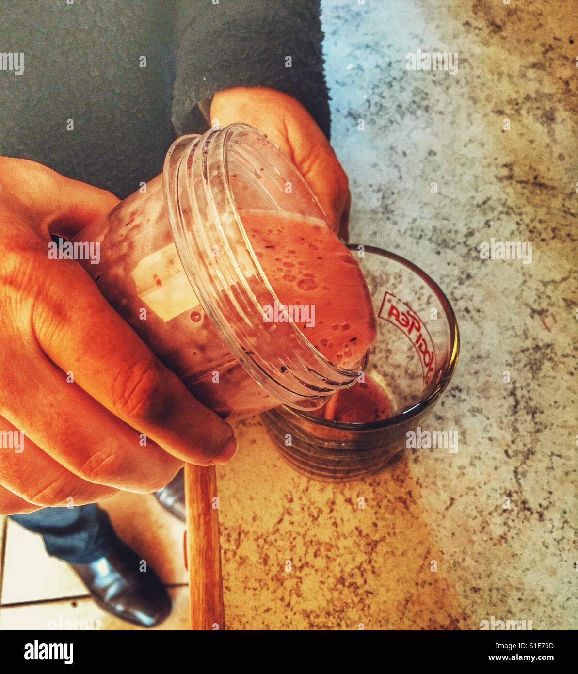 Woman in kitchen making homemade banana and strawberry fruit smoothie - Smartphone Captured Stock Image