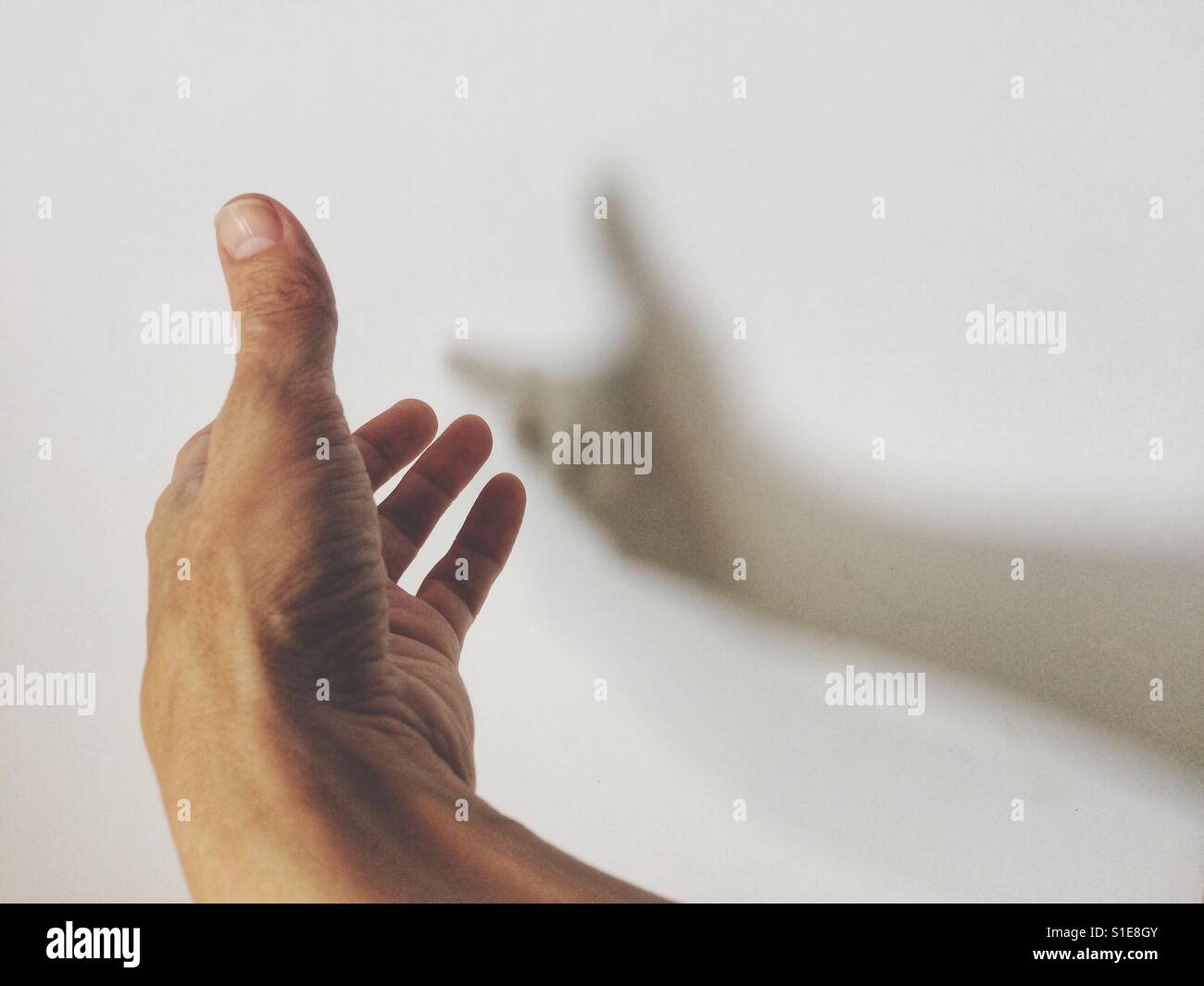 Male hand casting a shadow on the wall. Positive or hope concept. Stock Photo