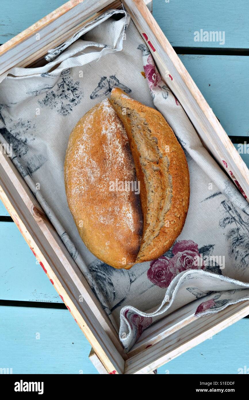 A loaf of artisanal bread in a rustic bread basket. Stock Photo