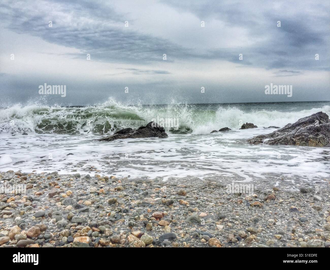 Waves crashing around rocks as the tide comes in on beach - Smartphone Captured Stock Image