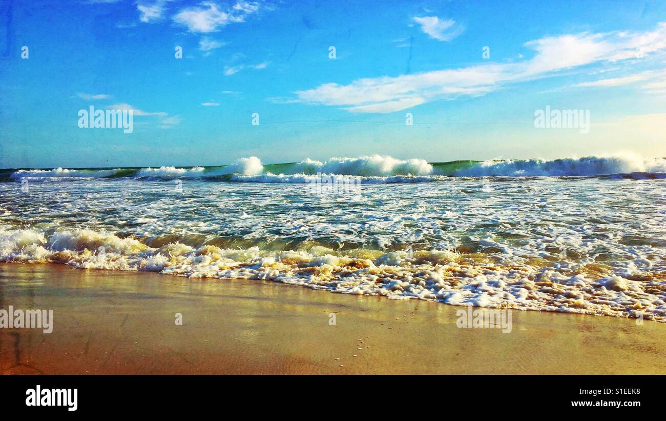 View from sandy beach of breaking waves on the horizon. 16x9. Space for copy. - Smartphone Captured Stock Image