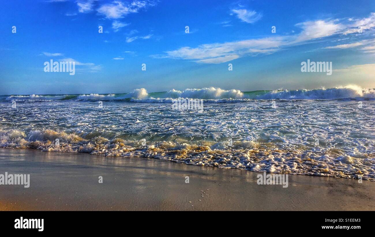 View of ocean waves crashing onto a sandy beach. Low angle shot. 16x9 crop. Space for copy. - Smartphone Captured Stock Image