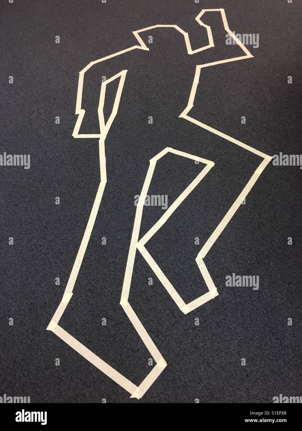 Masking tape outline of the human form on a carpeted floor. Stock Photo
